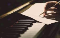 钢琴琴键上写谱子的手特写